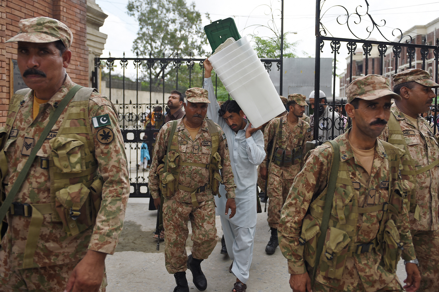 Pakistani army soldier walk alongside a presiding officer (C) carrying ballot boxes as they come out from the voting materials distribution centre in Rawalpindi on July 24, 2018. (AFP/File)
