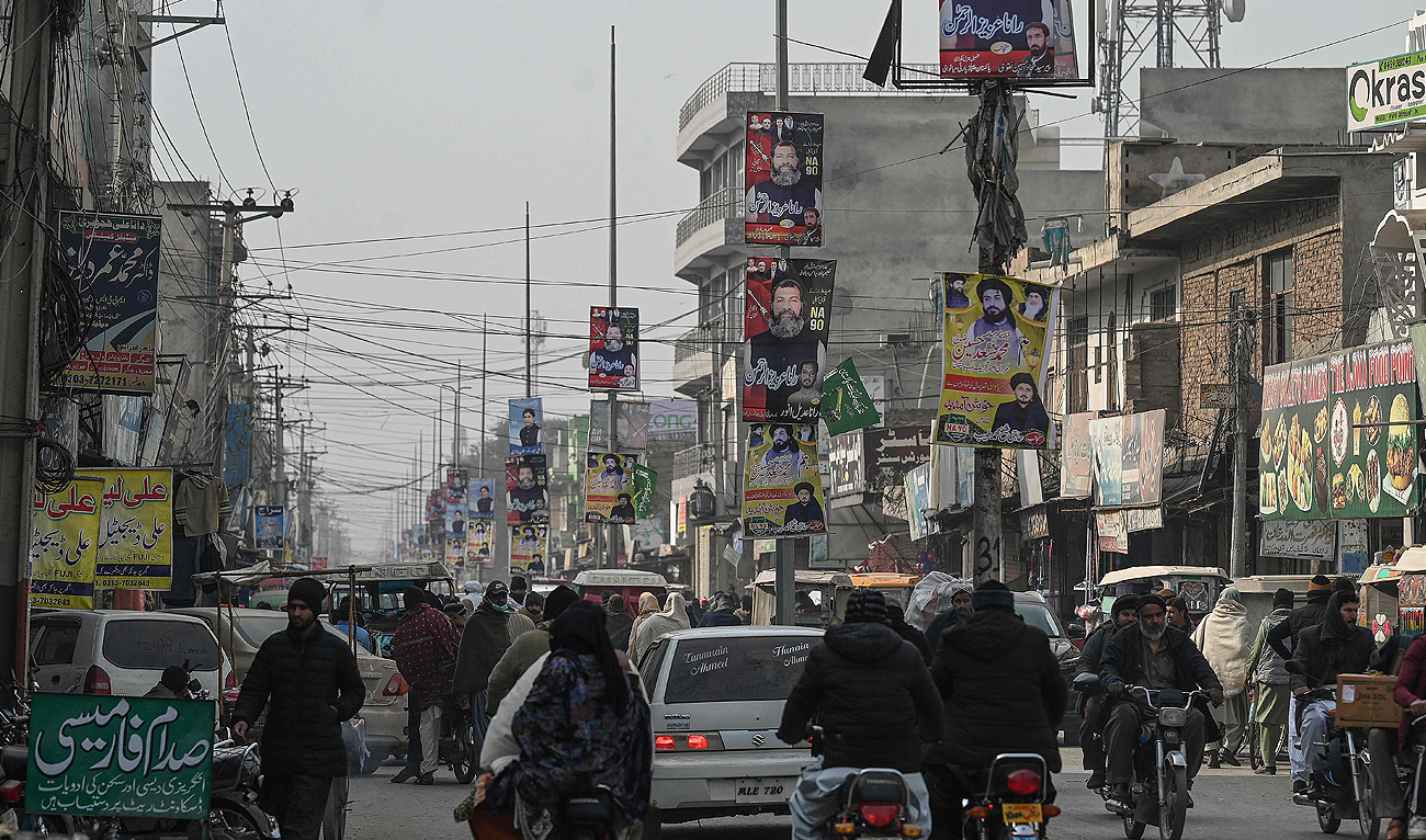 In this picture taken on January 17, 2024, people make their way along a busy street with election campaign posters of different parties displayed in Mianwali, the native town of Pakistan’s jailed former Prime Minister Imran Khan in Punjab Province. (AFP)