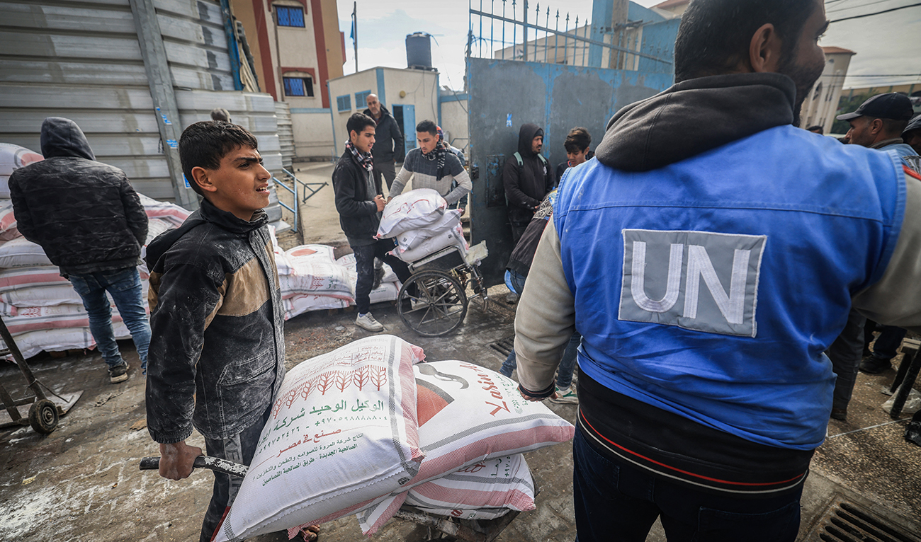 Displaced Palestinians receive food aid at the United Nations Relief and Works Agency for Palestine Refugees (UNRWA) center in Rafah in the southern Gaza Strip on January 28, 2024. (AFP/File)