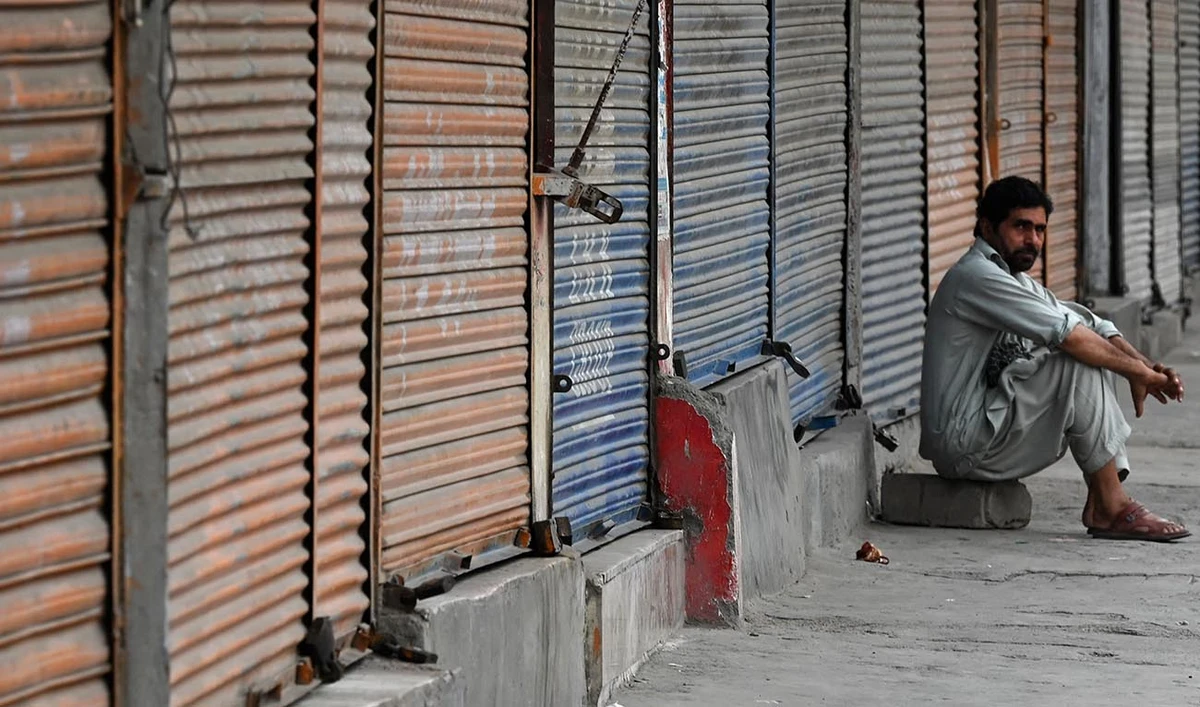 A man sits in front of closed shops along a roadside in Peshawar on September 2, 2023. (AFP/File)