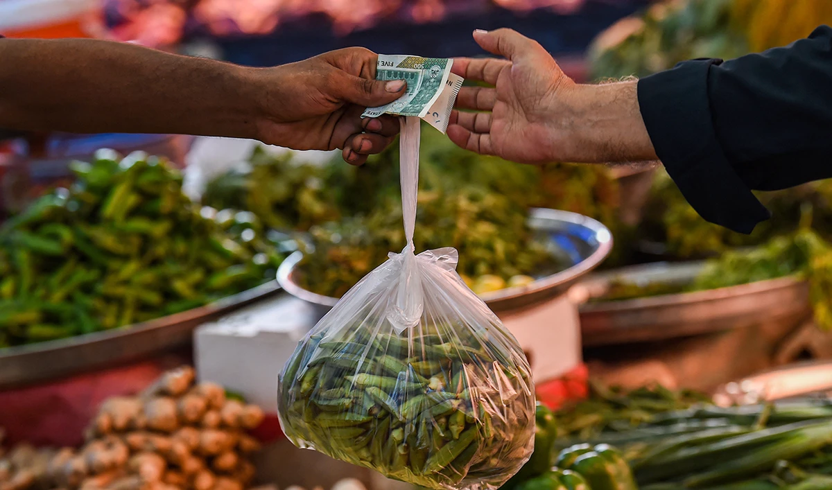A customer buys vegetables from a stall at a market in Karachi on July 3, 2023. (AFP/File)