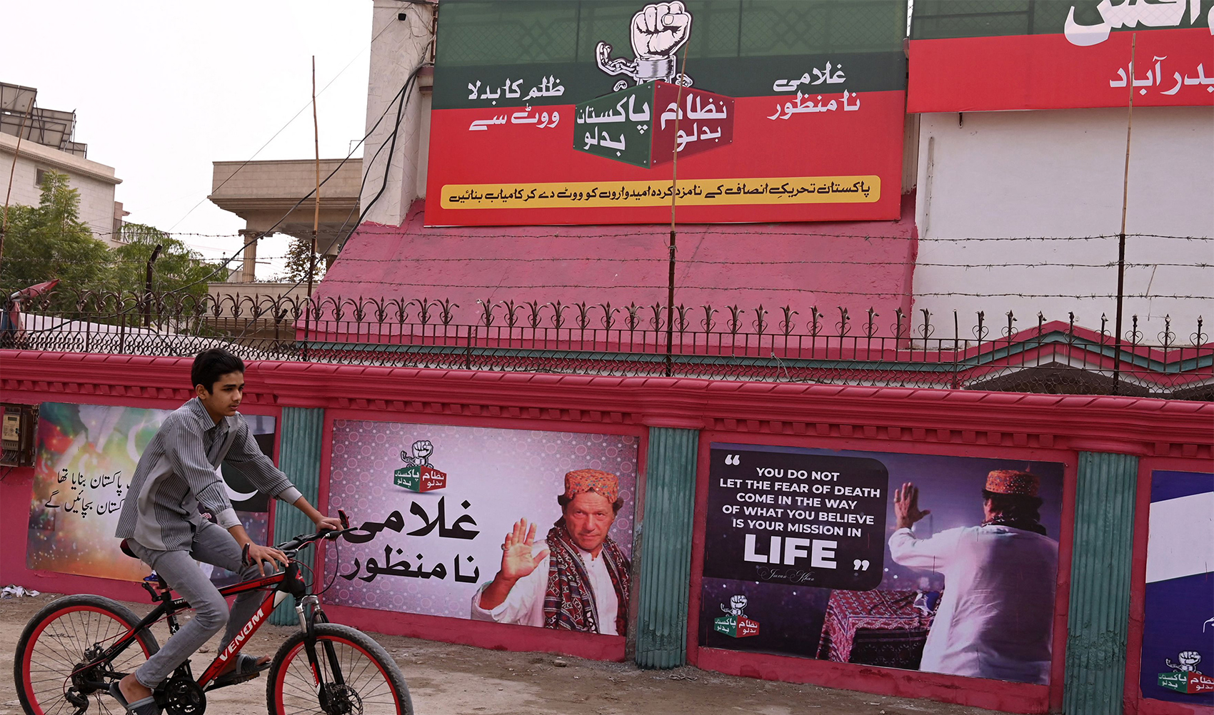 A boy rides past a wall posters with images of Pakistan's former Prime Minister Imran Khan in Hyderabad on January 30, 2024. (AFP)