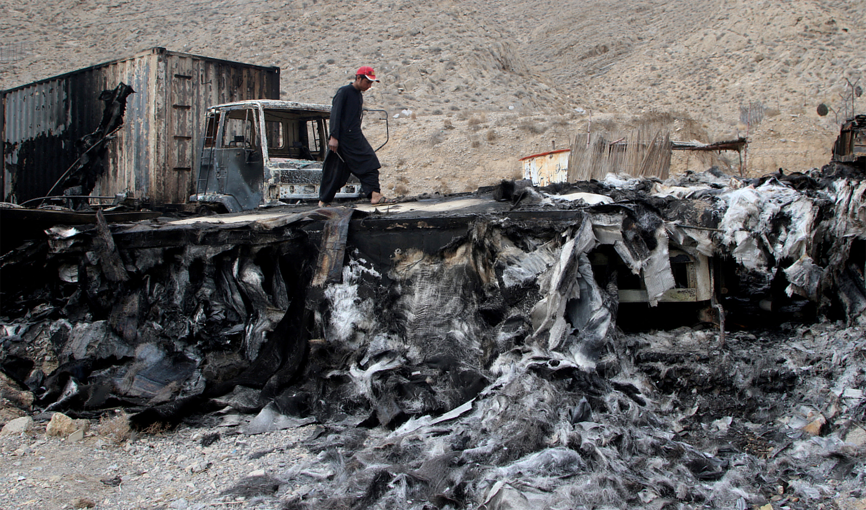A man walks on a damaged truck trailer after an attack by unidentified armed men in Kolpur, near Quetta, Pakistan, on January 30, 2024. (REUTERS)