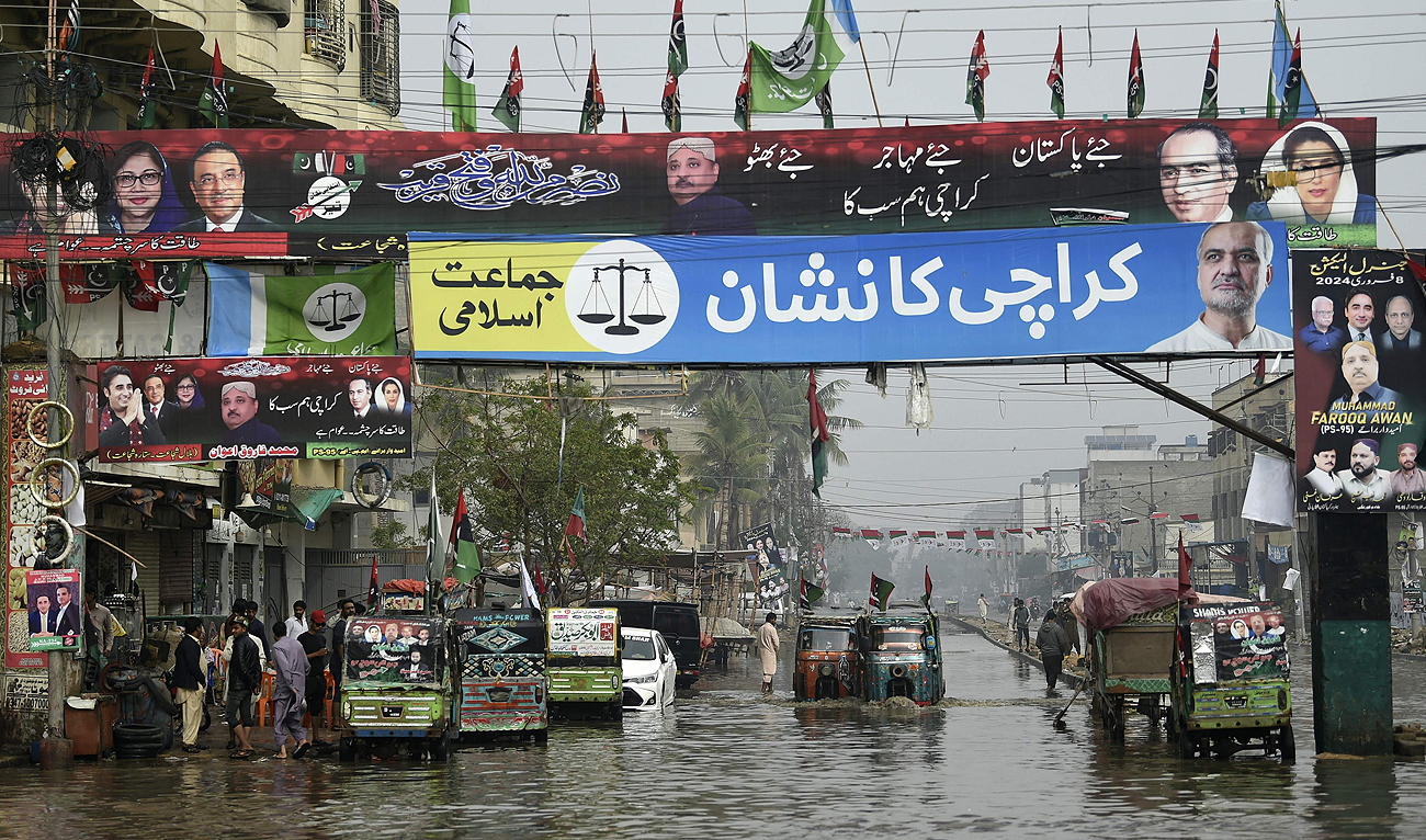 Election posters and banners of the Pakistan Peoples Party (PPP) and Jamaat-e-Islami party are seen across a flooded street in Karachi on February 4, 2024, ahead of the upcoming general elections. (AFP)
