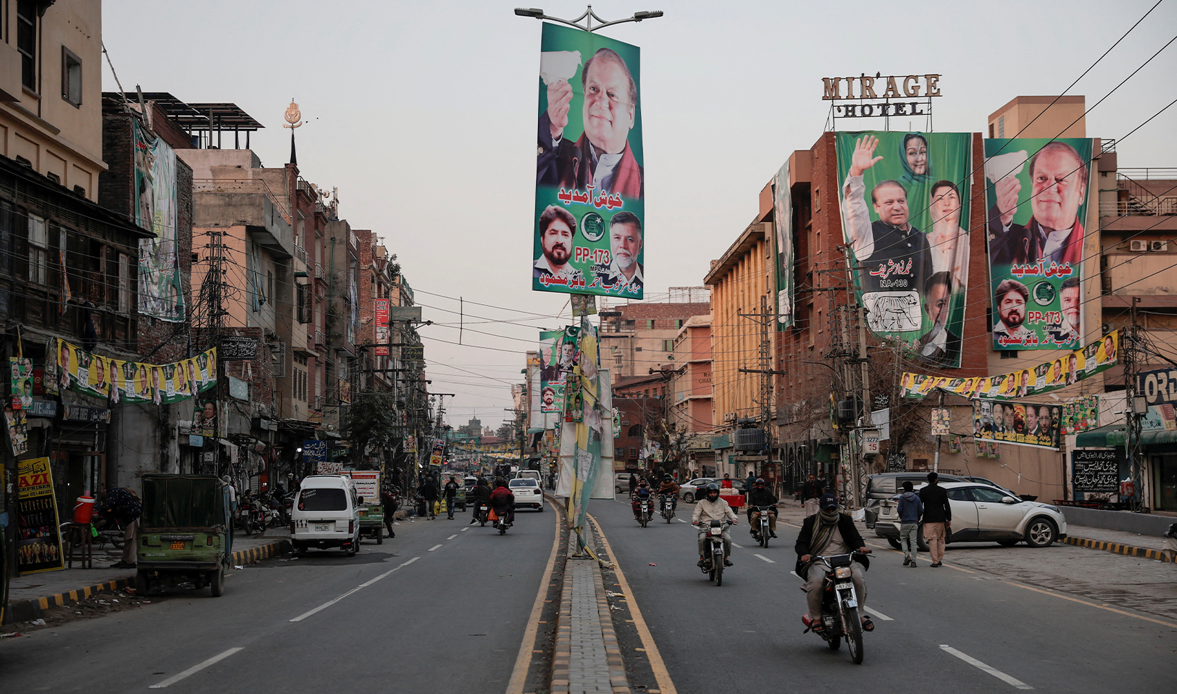 People commute on a street filled with campaign banners and posters of a political party, ahead of the general elections, in Lahore, Pakistan, on February 5, 2024. (REUTERS)