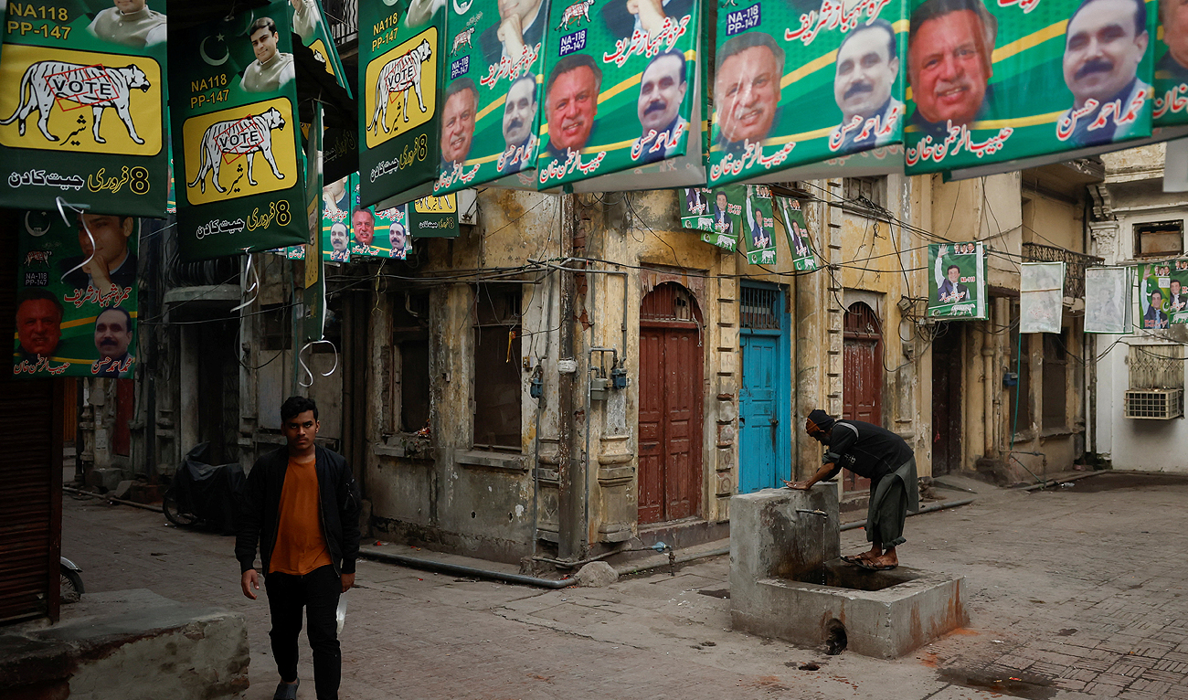 A man walks along a street filled with campaign posters a day ahead of the general election, at the Walled City in Lahore, Pakistan February 7, 2024. (REUTERS)