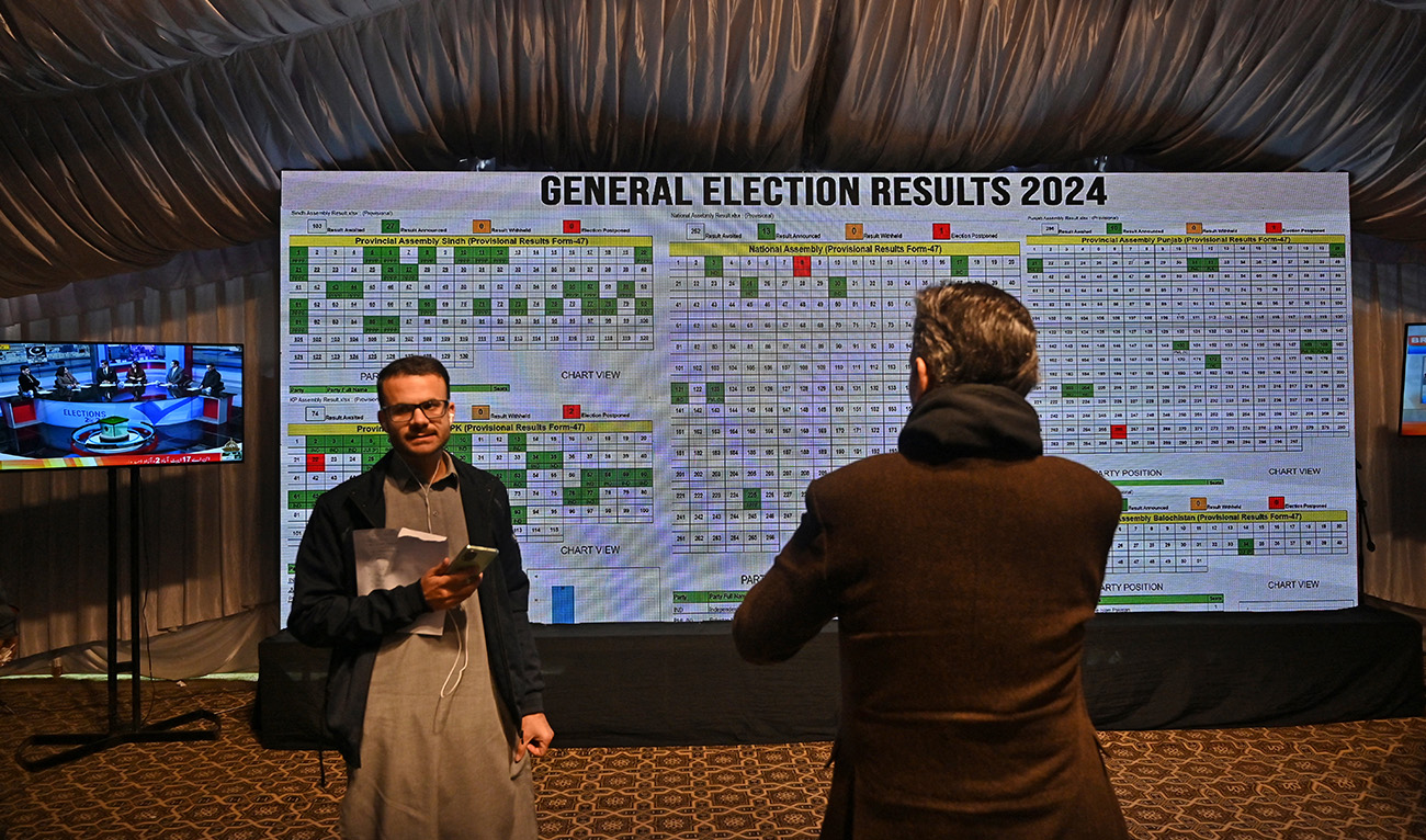 Journalists stand in front of a screen showing live results in the Election Commission office in Islamabad on February 9, 2024, a day after Pakistan's national elections. (AFP)