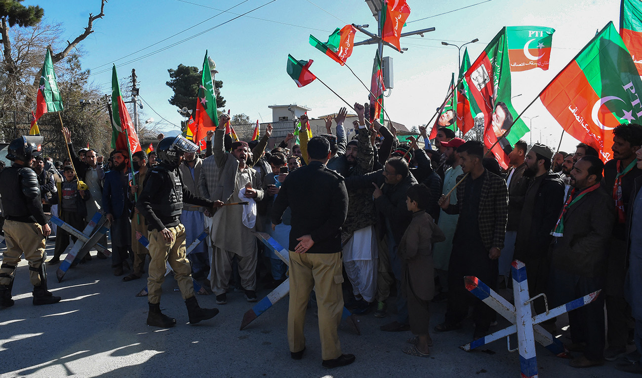 Police personnel stand guard as supporters of Pakistan Tehreek-e-Insaf (PTI) and other parties protest outside the office of a Returning Officer in Quetta on February 9, 2024, against the alleged rigging in Pakistan's national election results. (AFP)