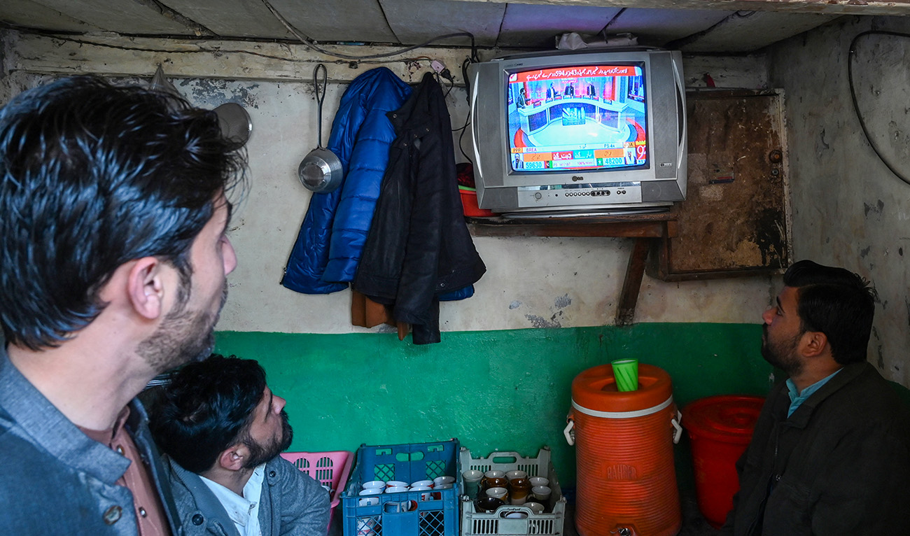People monitor latest election results live on a television at a tea shop, a day after Pakistan's national elections in Lahore on February 9, 2024. (AFP)