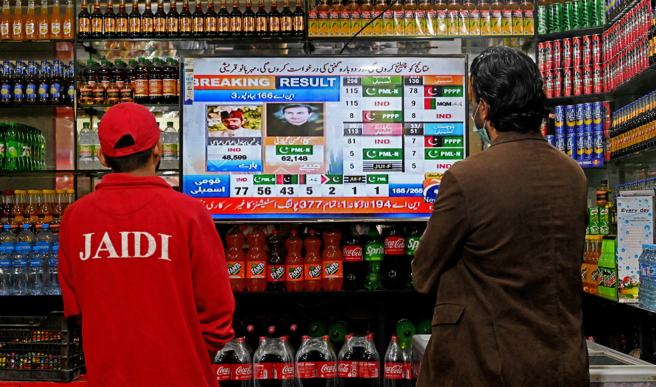 People watch latest election results live on a television at a shop, a day after Pakistan's national elections in Lahore on February 9, 2024. (AFP)
