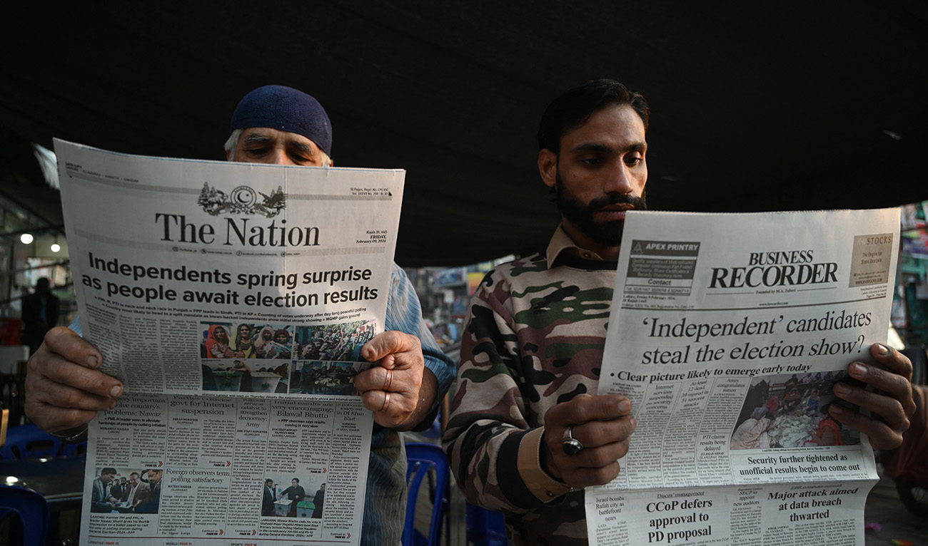 People reads morning newspapers with the front page election headlines along a roadside stall a day after Pakistan's national general election in Lahore on February 9, 2024. (AFP/File)