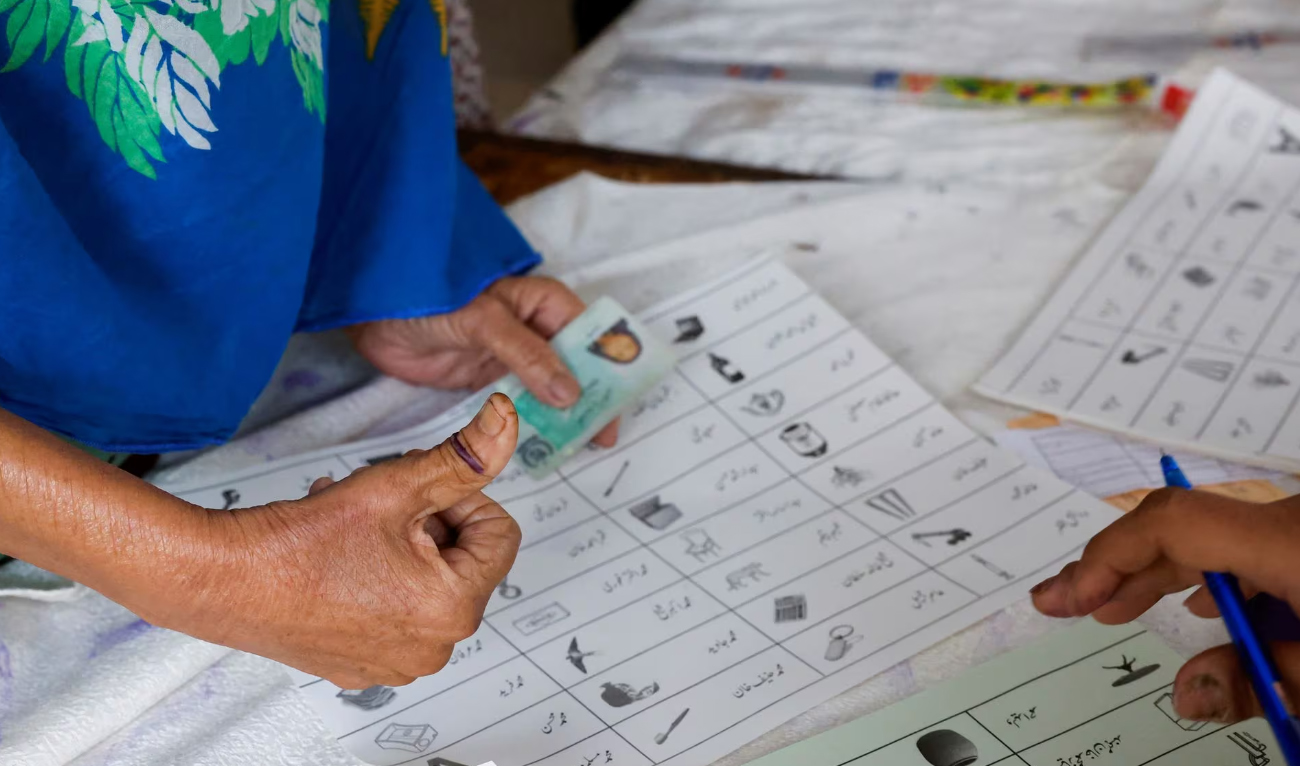 A voter with an ink mark on the thumb goes through paperwork to cast a vote during the general election in Karachi, Pakistan February 8. (REUTERS)