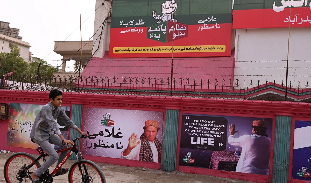 A boy rides past a wall posters with images of Pakistan's former Prime Minister Imran Khan in Hyderabad on January 30, 2024. (AFP)