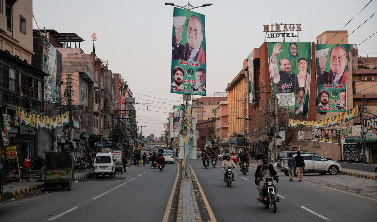 People commute on a street filled with campaign banners and posters of a political party, ahead of the general elections, in Lahore, Pakistan, on February 5, 2024. (REUTERS)