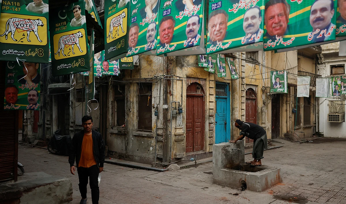 A man walks along a street filled with campaign posters a day ahead of the general election, at the Walled City in Lahore, Pakistan February 7, 2024. (REUTERS)