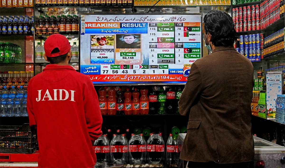 People watch latest election results live on a television at a shop, a day after Pakistan's national elections in Lahore on February 9, 2024. (AFP/File)