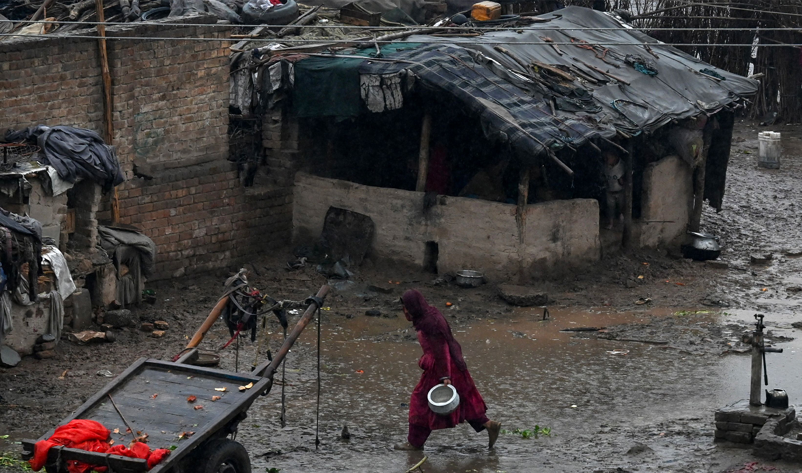 A woman runs towards a shade amid a drizzle in Peshawar, Pakistan, on March 1, 2024. (AFP)