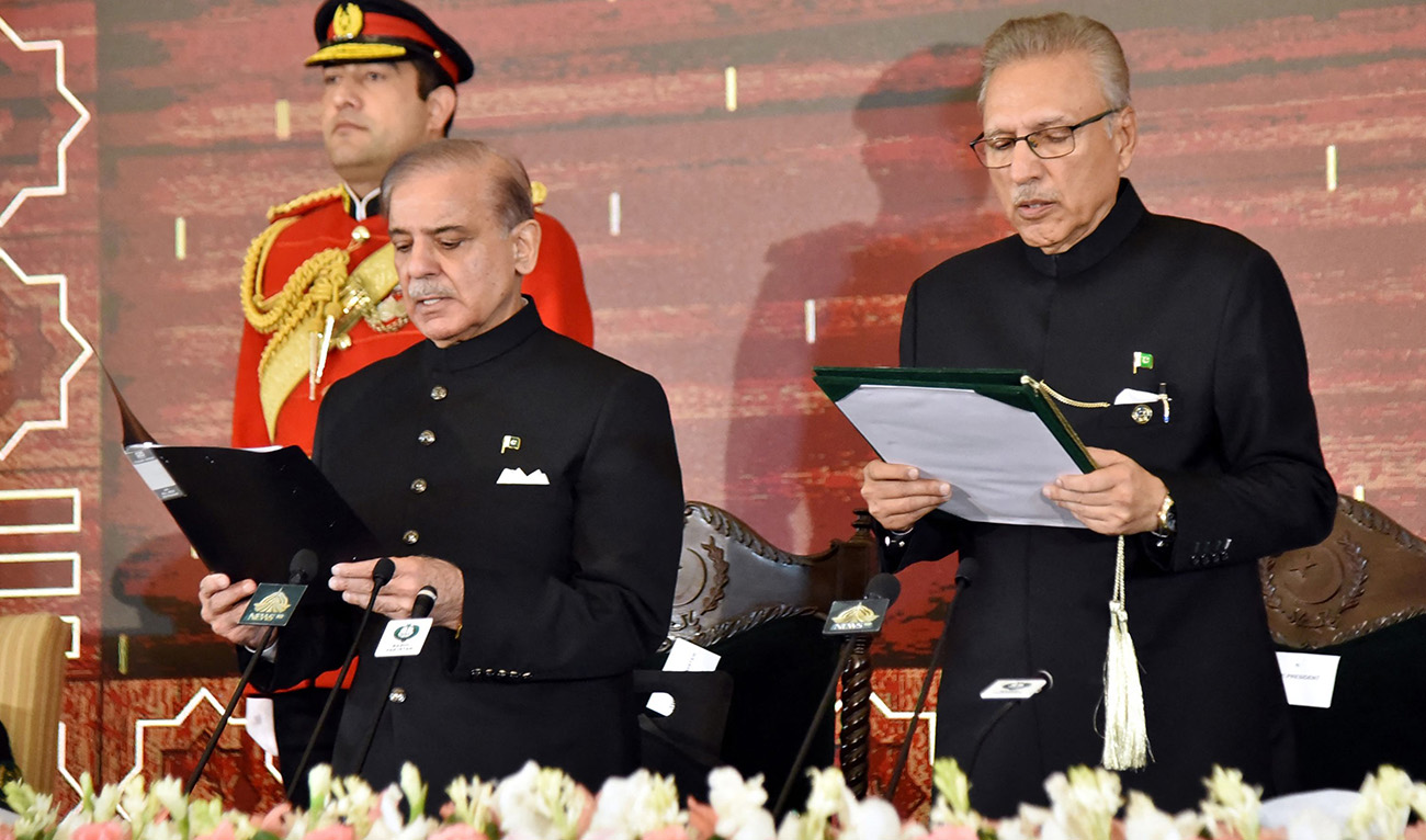 In this handout photograph taken and released by the Pakistan President House on March 4, 2024, Pakistan's President Arif Alvi (R) administers the oath to newly sworn-in Prime Minister Shehbaz Sharif (C) at the President House in Islamabad. (President House)