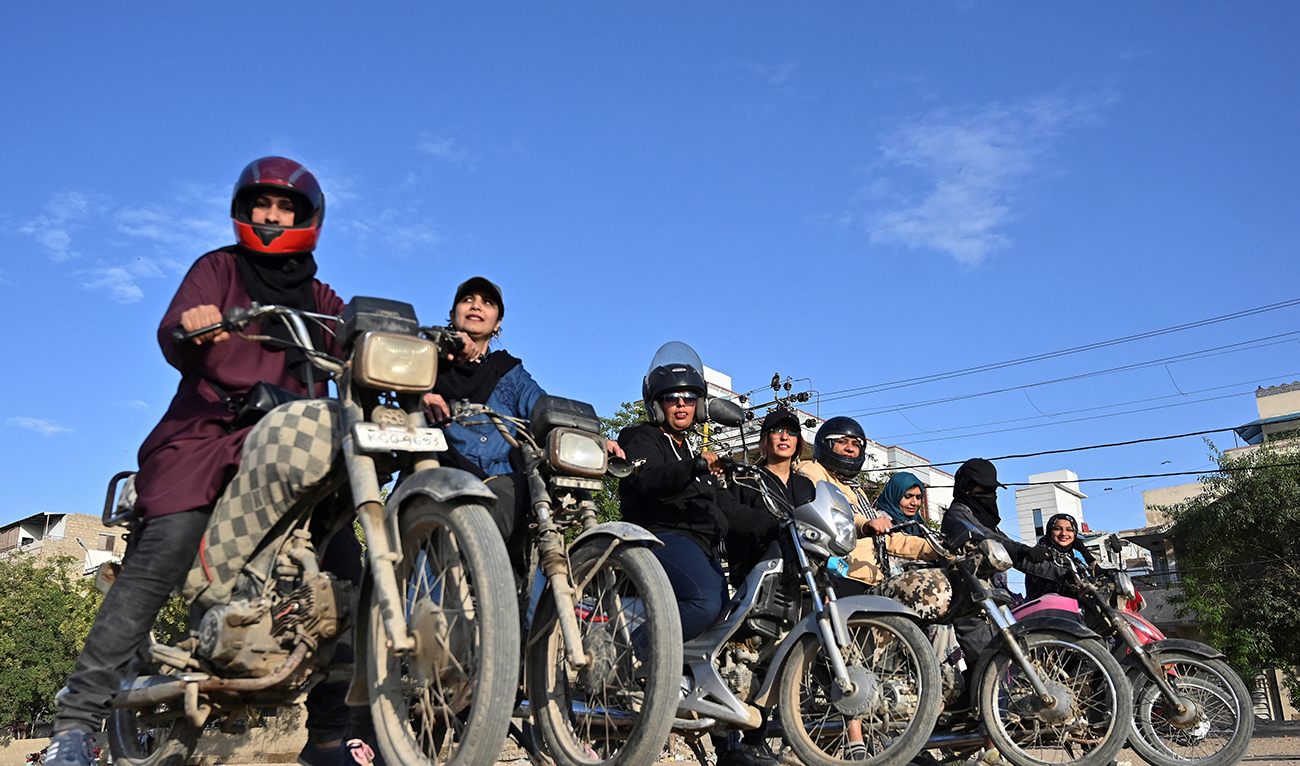 In this picture taken on March 5, 2024, members and students of the women-only group "Rowdy Riders" line up before riding their bikes during a riding lesson at an open ground in Karachi. (AFP)