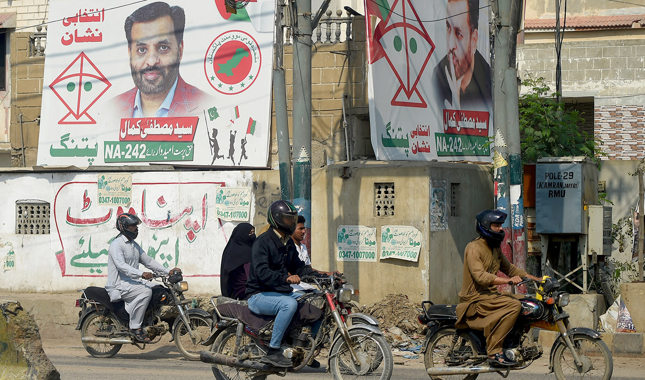 This photograph taken on February 15, 2024, shows commuters riding past election campaign posters of Syed Mustafa Kamal, senior deputy convener of the Muttahida Qaumi Movement-Pakistan (MQM-P) party, along a street in Karachi. (AFP/File)