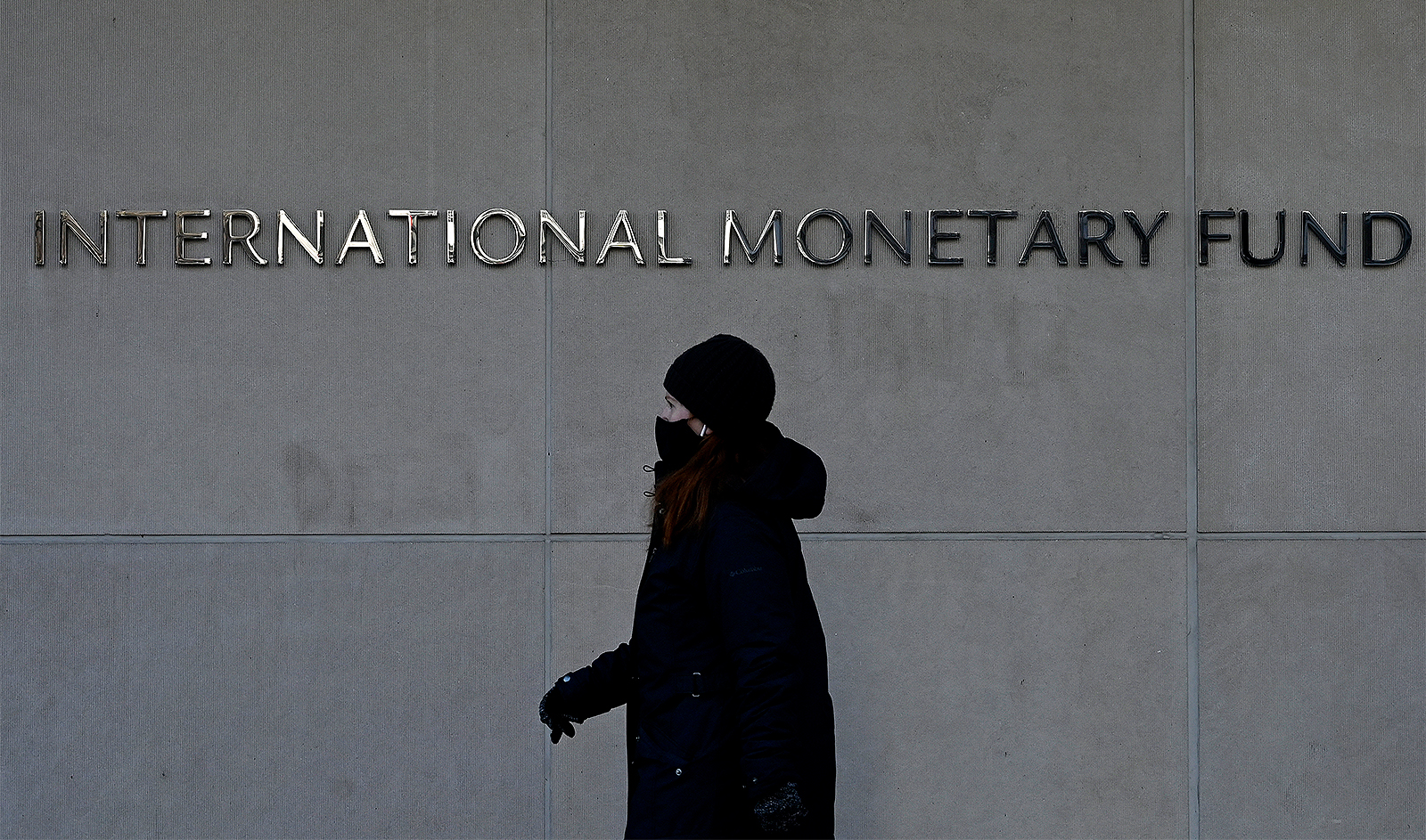 A woman walks past the International Monetary Fund headquarters in Washington, DC, on January 26, 2022. (AFP/File)