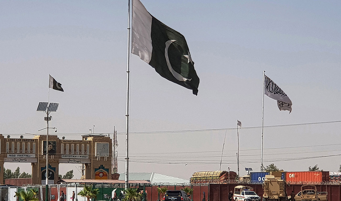 Pakistani flags (C) and Taliban flag (R) flutter on their respective border sides as seen from the Pakistan-Afghanistan border crossing point in Chaman on August 18, 2021. (AFP/File)