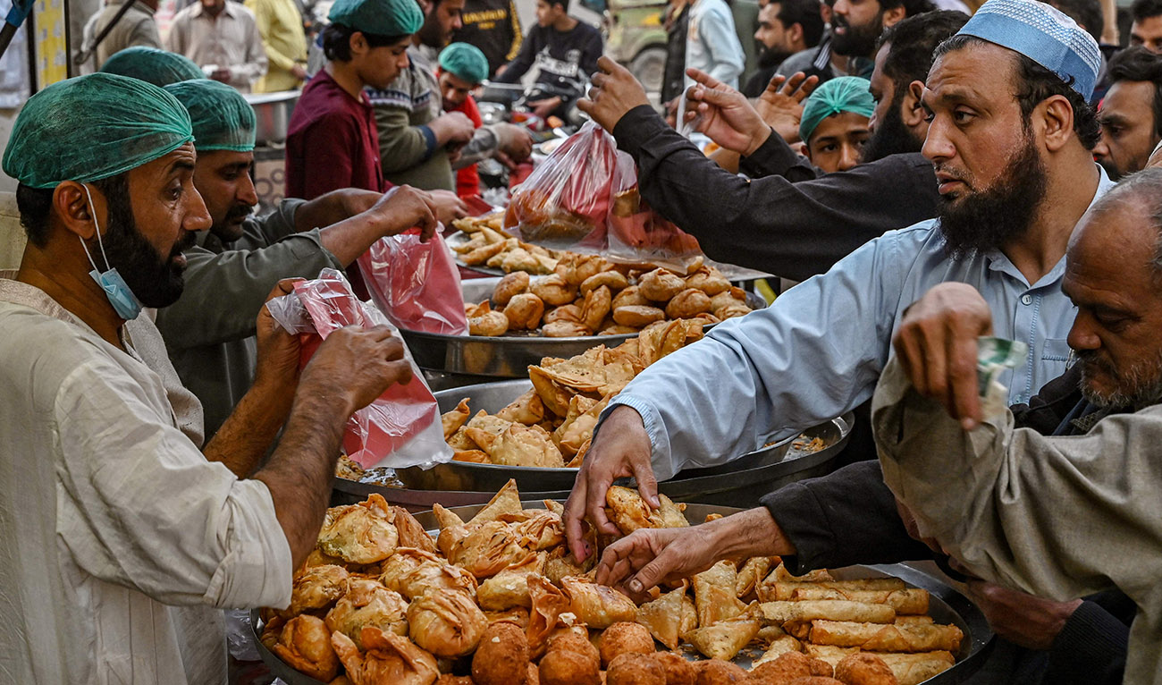 Muslim devotees buy Iftar food before breaking their fast on the first day of the Islamic holy month of Ramadan, at a market in Lahore on March 12, 2024. (AFP)