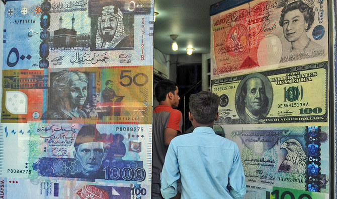 Pakistani customers enter a foreign currency exchange shop in Karachi, Pakistan, on October 14, 2010. (AFP/File)