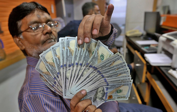 A Pakistani money trader checks U.S. 100 dollar notes at a currency exchange office, in Karachi, Pakistan, on May 19, 2022. (AP/File)