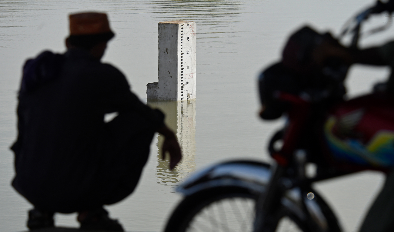 In this file photo, taken on August 28, 2022, a resident from the nearby neighbourhood looks on the water level scale of river Indus in flood hit Sukkur of Sindh province. (AFP/File)