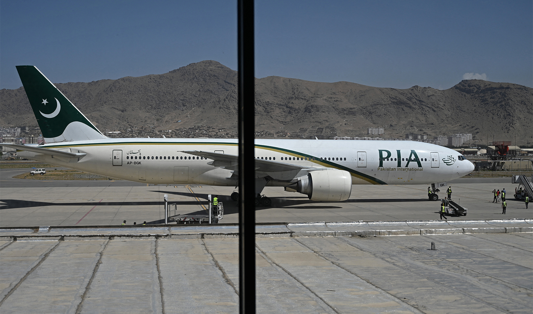 Members of ground staff stand on the tarmac beside a Pakistan International Airlines (PIA) aircraft at the airport in Kabul, Afghanistan on September 13, 2021. (AFP/File)