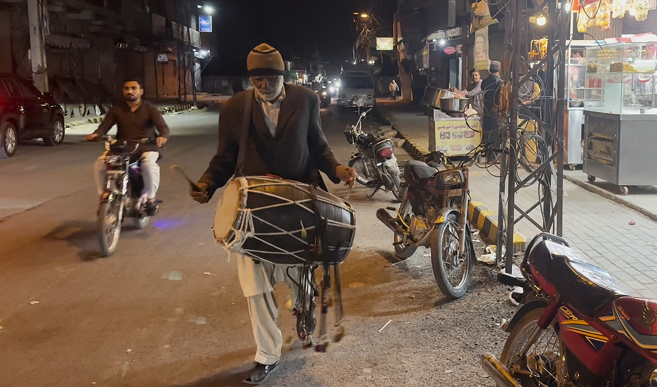 In this picture taken on March 25, 2024, a Pakistani man Imam Buksh (C), 63, ‘Ramadan drummer’ beats his drum as he makes calls at doors “Wake up and eat your sehri morning meal” before their fasting during Ramadan at Satellite Town, a residential area, in Rawalpindi. Buksh is one of the few drummers who still perform the centuries-old duty of waking people up during Ramadan nights to eat their pre-dawn meals. (AN Photo)