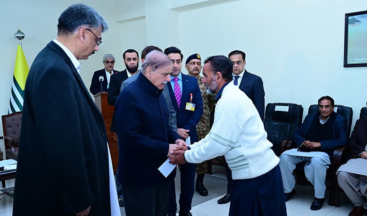 In this handout photo, taken and released by Prime Minister’s Office, Prime Minister Shehbaz Sharif interacts with a man while distributing assistance cheques to the families of the victims of recent torrential rains and heavy snowfall in Muzaffarabad, Azad Kashmir on March 8, 2024. (Photo courtesy: GOP)