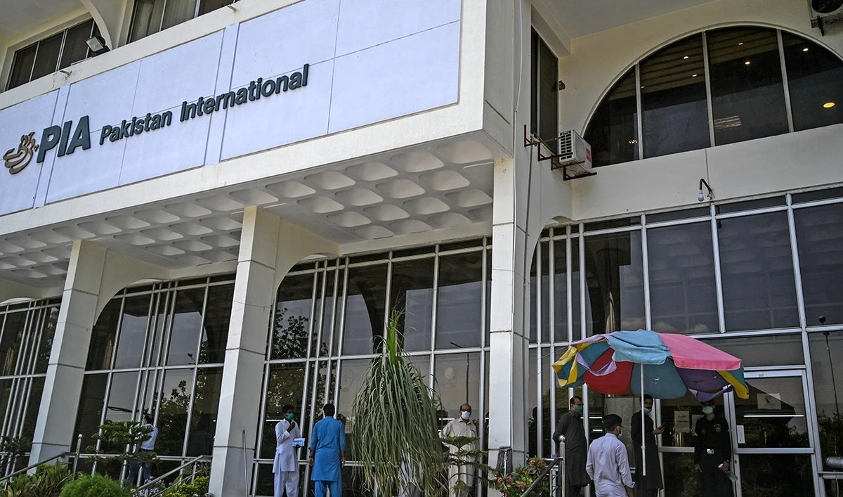 People stand in queue as they wait their turn to buy flight tickets outside Pakistan International Airlines (PIA) office in Islamabad on July 1, 2020. (AFP/File)