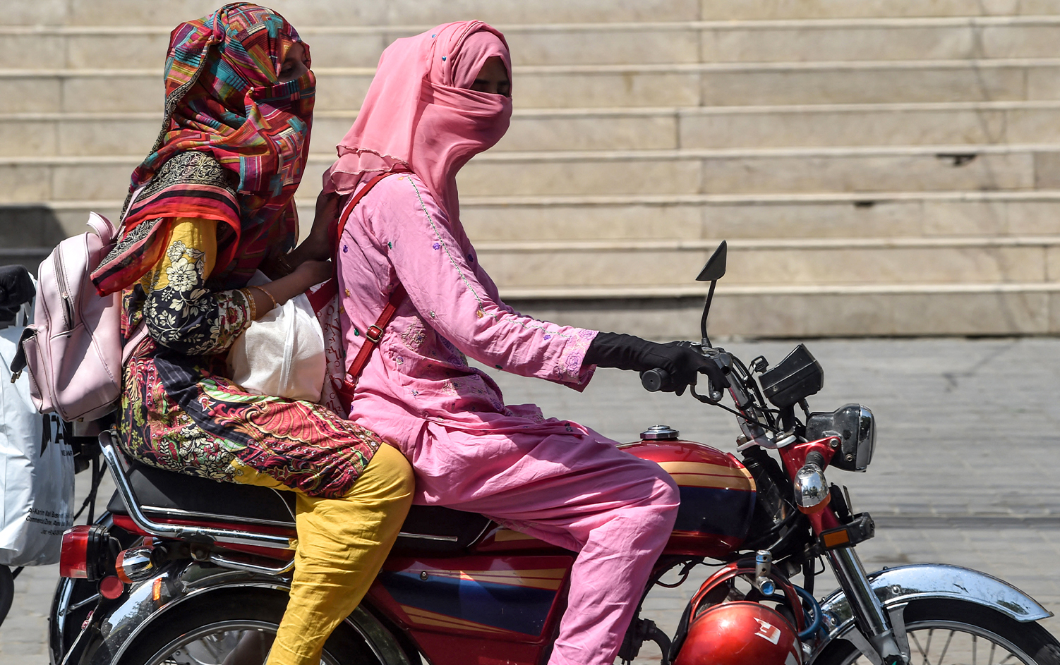 Women covering their faces ride a motorbike on a street during heatwave, as temperatures reach 40 degrees celsius, in Lahore on May 27, 2020. (AFP/File)