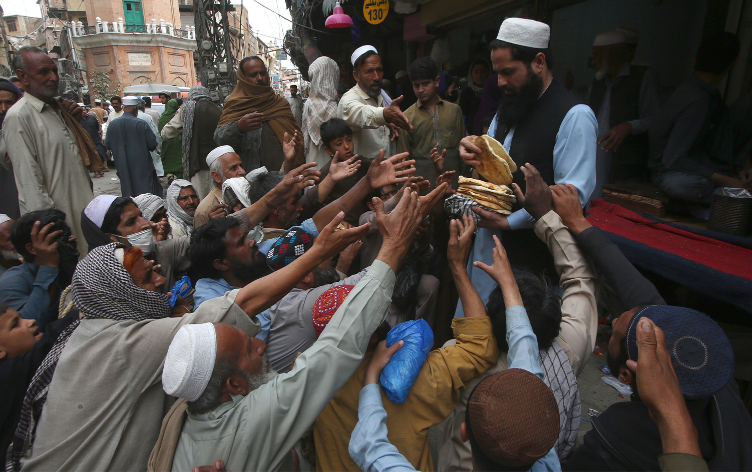 People receive free bread distributed by a volunteer for breaking their fast during the Muslim's holy fasting month of Ramadan outside a restaurant in Peshawar, Pakistan, on April 4, 2024. (AP)