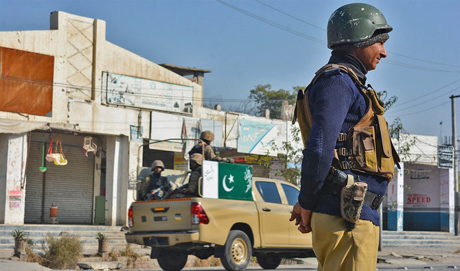 A policeman (R) and army soldiers (L) stand guard along a road in Bannu on December 21, 2022. (AFP/File)