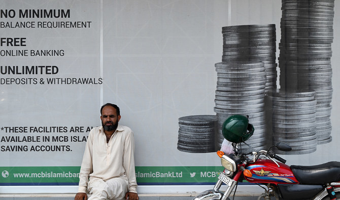 A man sits outside a bank along a street in Rawalpindi, Pakistan on July 15, 2023. (AFP/File)