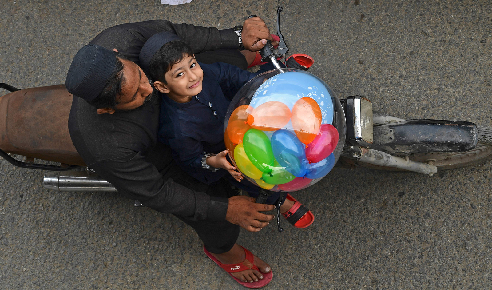 A boy carries a balloon on a motorbike after offering Eid al-Fitr prayers, marking the end of the holy fasting month of Ramadan, in Karachi on April 10, 2024. (AFP)
