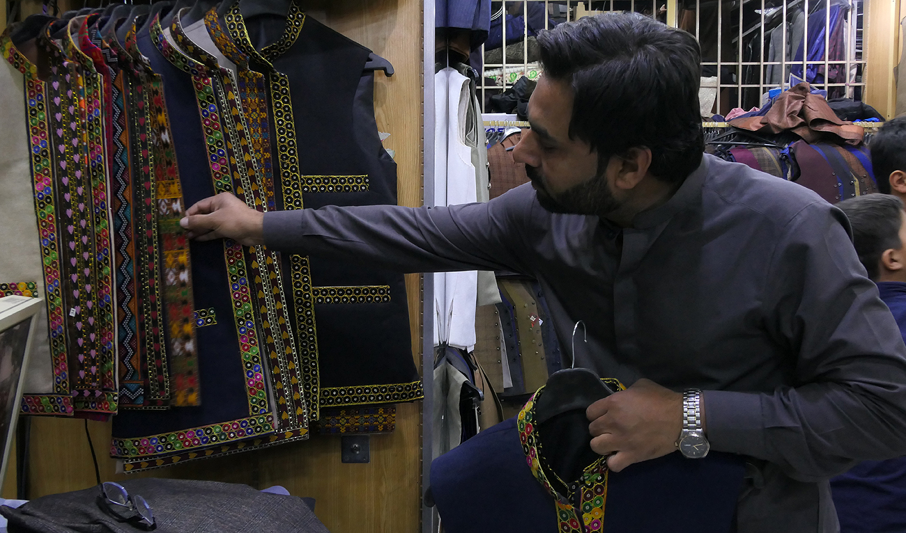 In this photograph, taken on April 04, 2024, a customer, Sarfaraz Ahmed, looks waistcoats at display at a shop in Quetta, ahead of Eid Al-Fitr holidays. (AN Photo)