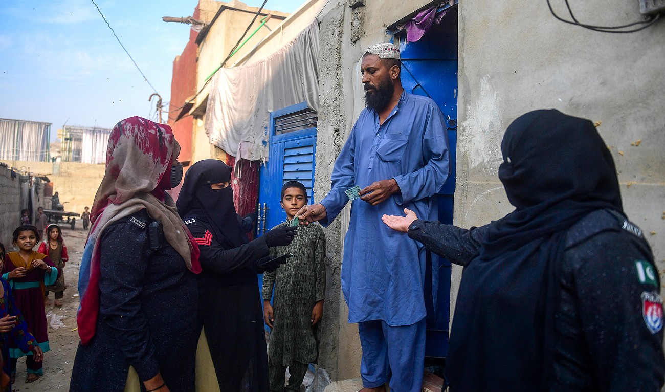 In this file photo, taken on November 17, 2023, police personnel check documents of Afghan refugees during a search operation to identify alleged illegal immigrants, on the outskirts of Karachi. (AFP/File)