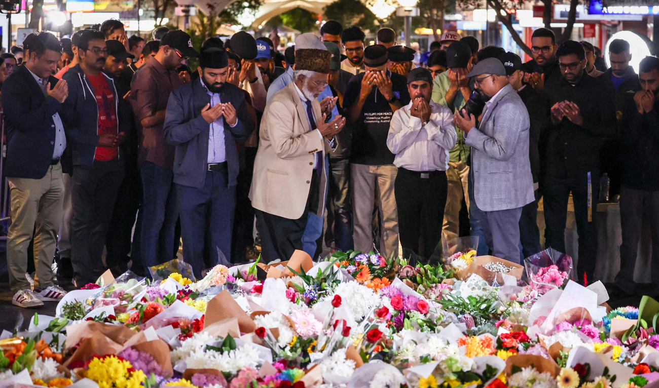 Members of the Ahmadiyya Muslim Community of Australia offer prayers in front of flowers left outside the Westfield Bondi Junction shopping mall in Sydney on April 14, 2024, the day after a 40-year-old knifeman with mental illness roamed the packed shopping center killing six people and seriously wounding a dozen others. (AFP)