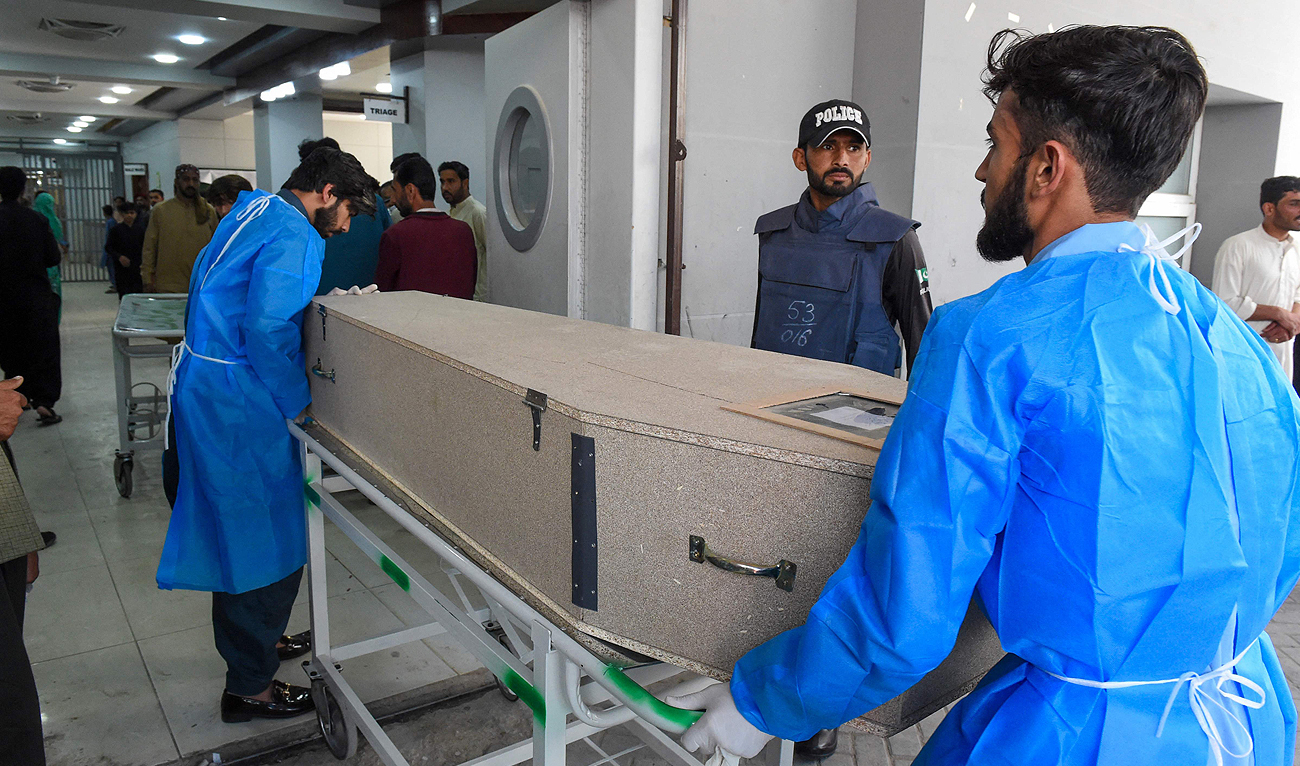 Paramedics carry slain migrant laborers’ coffins at a hospital in Quetta on April 13, 2024, after they were killed by gunmen near the city of Naushki in Balochistan province. (AFP)