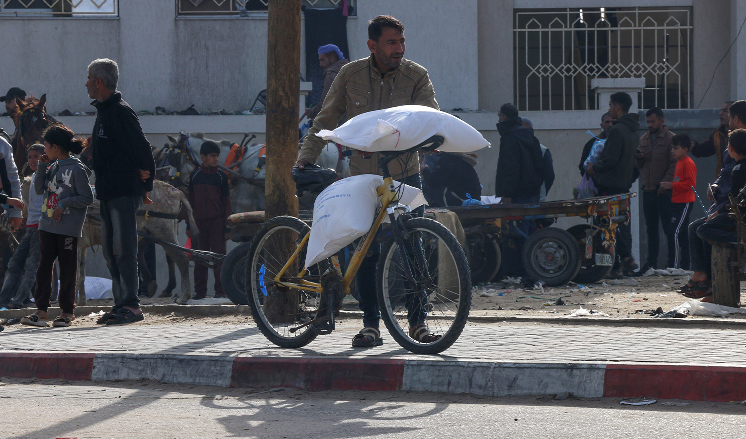Palestinians receive bags of flour at the United Nations Relief and Works Agency for Palestine Refugees (UNRWA) distribution center in the Rafah refugee camp in the southern Gaza Strip on November 21, 2023, (AFP/File)