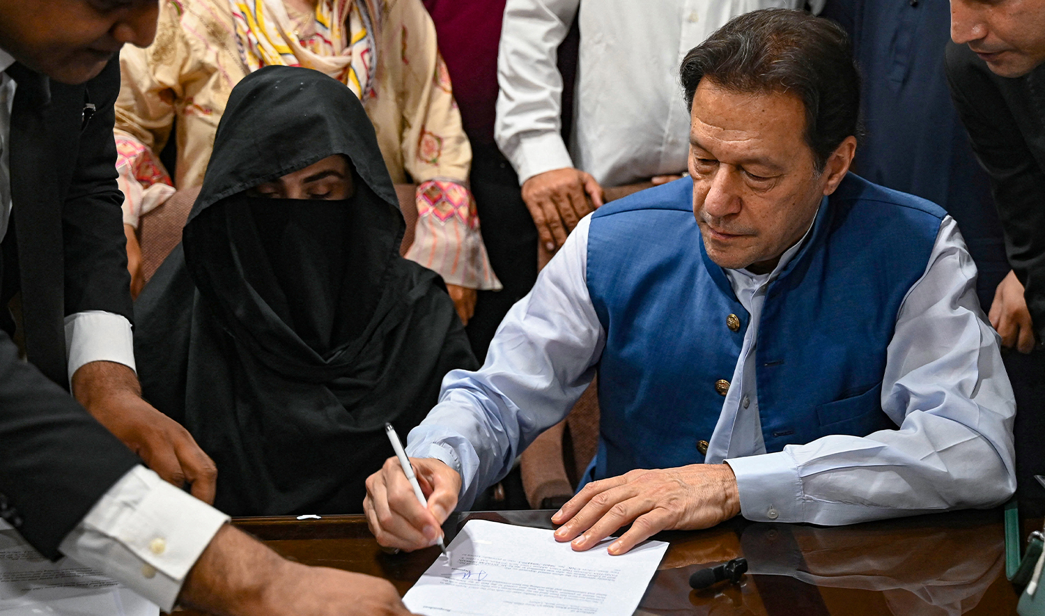 Pakistan's former Prime Minister, Imran Khan (R) along with his wife Bushra Bibi (C) signs surety bonds for bail in various cases, at a registrar office in the High court, in Lahore on July 17, 2023. (AFP/File)