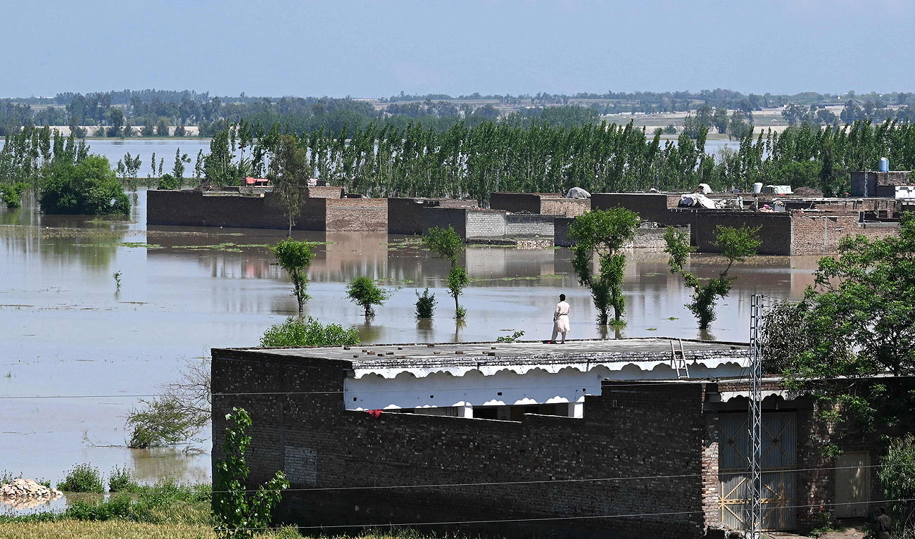 A man stands on the roof of his deluged house after heavy rains in Nowshera district, Khyber-Pakhtunkhwa province on April 16, 2024. (AFP)
