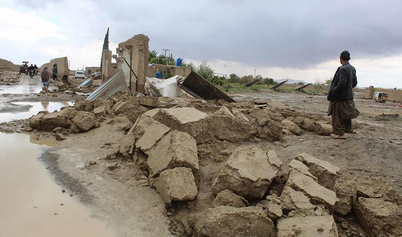Residents gather beside a damaged house after heavy rains on the outskirts of Chaman in Balochistan province on April 19, 2024. (AFP)