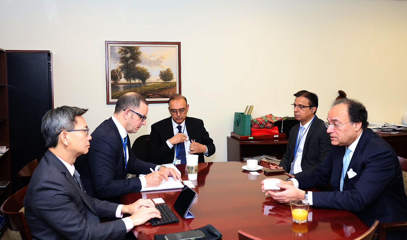 In this handout photograph, taken and released by Pakistan’s finance ministry, Pakistan Finance Minister Muhammad Aurangzeb (R) speaks to S&P Global and Fitch Ratings representatives on the sidelines of IMF and World Bank Spring meetings in Washington on April 20, 2024. (Photo courtesy: Finance Ministry)