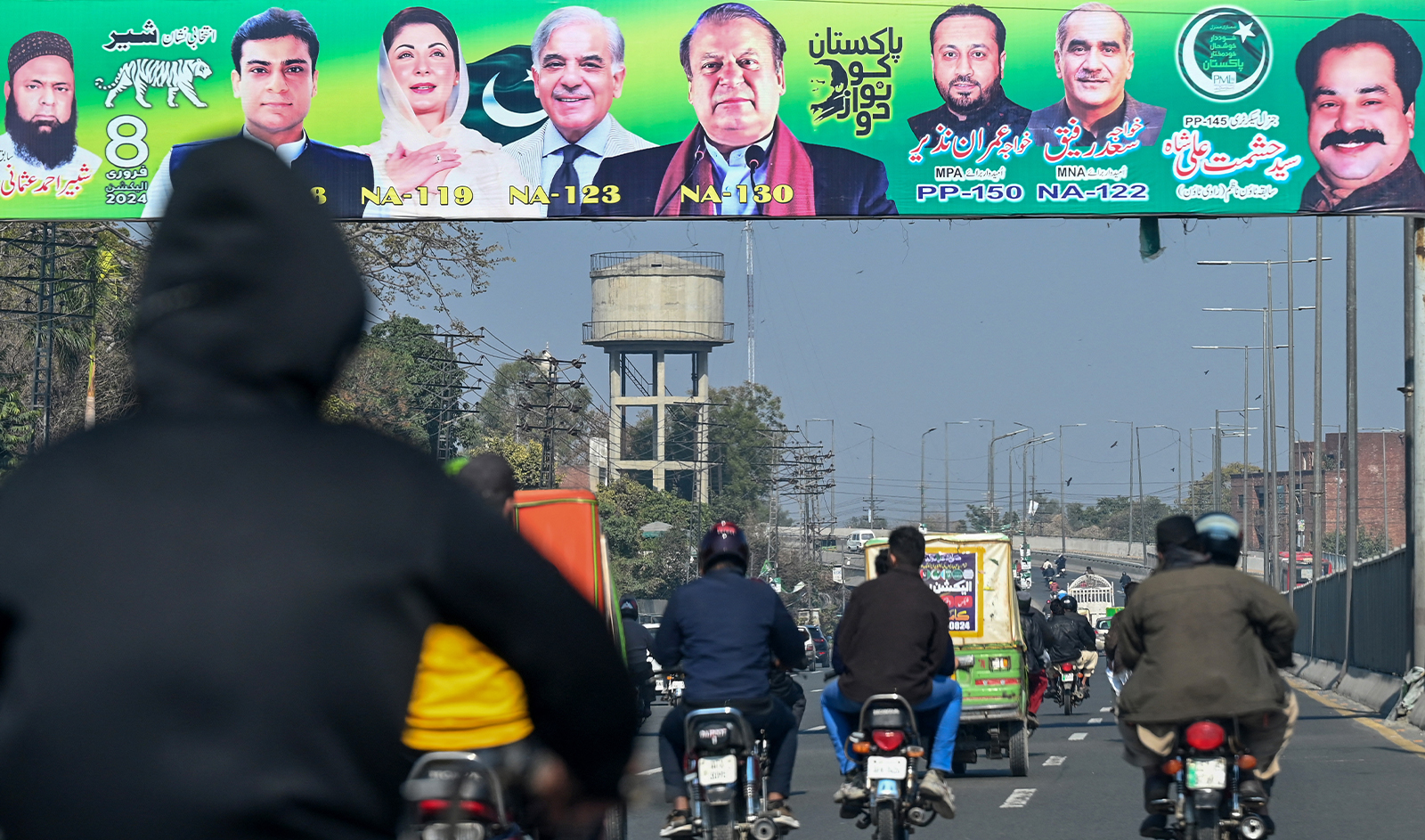 Commuters ride past posters of Nawaz Sharif (C) Pakistan's former Prime Minister and leader of the Pakistan Muslim League (PML) party, a day after national elections in Lahore on February 9, 2024. (AFP/File)