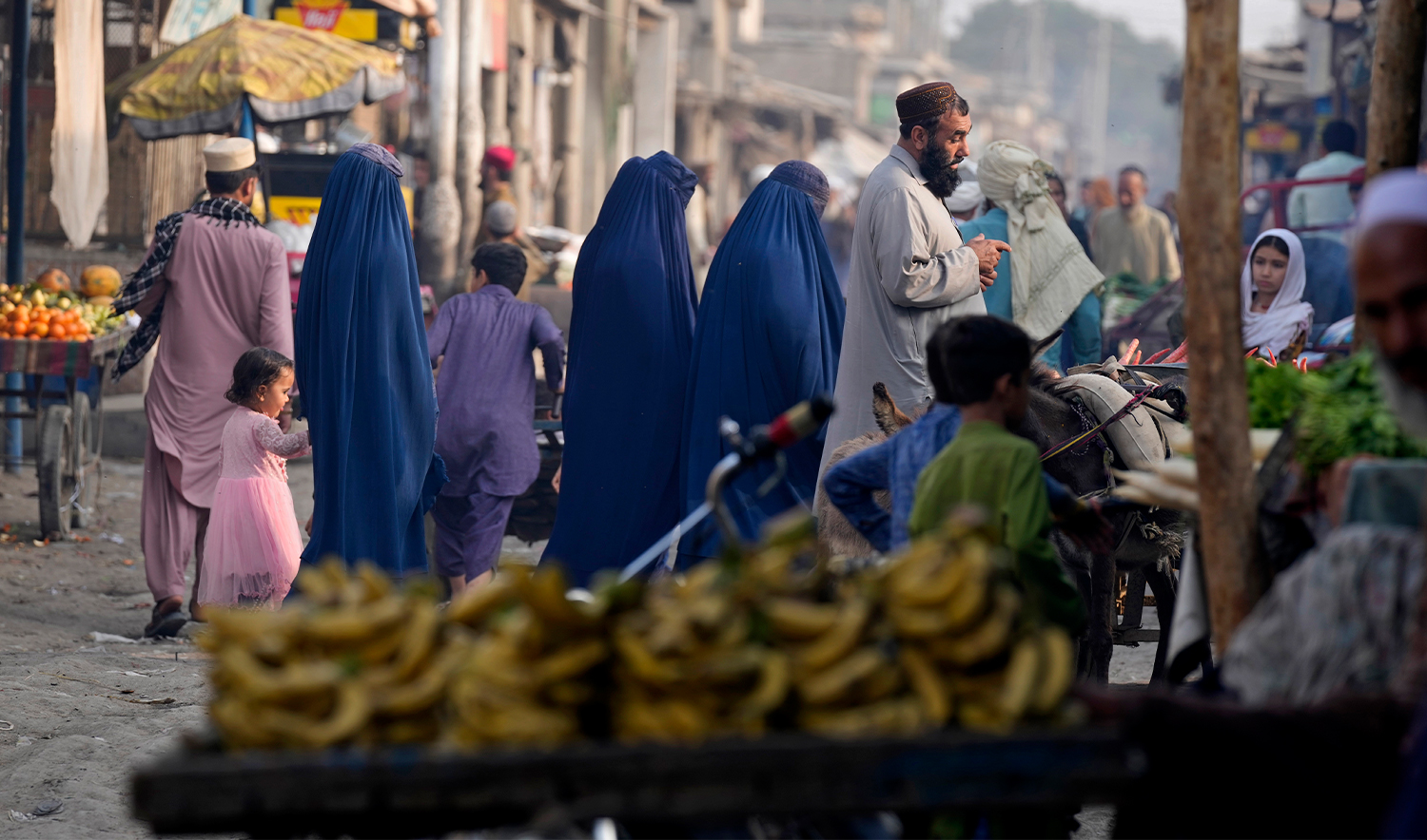 Burqa-clad Afghan women walk on a street with other in a a neighbourhood, where mostly Afghan populations, in Karachi, Pakistan, on January 26, 2024. (AP)